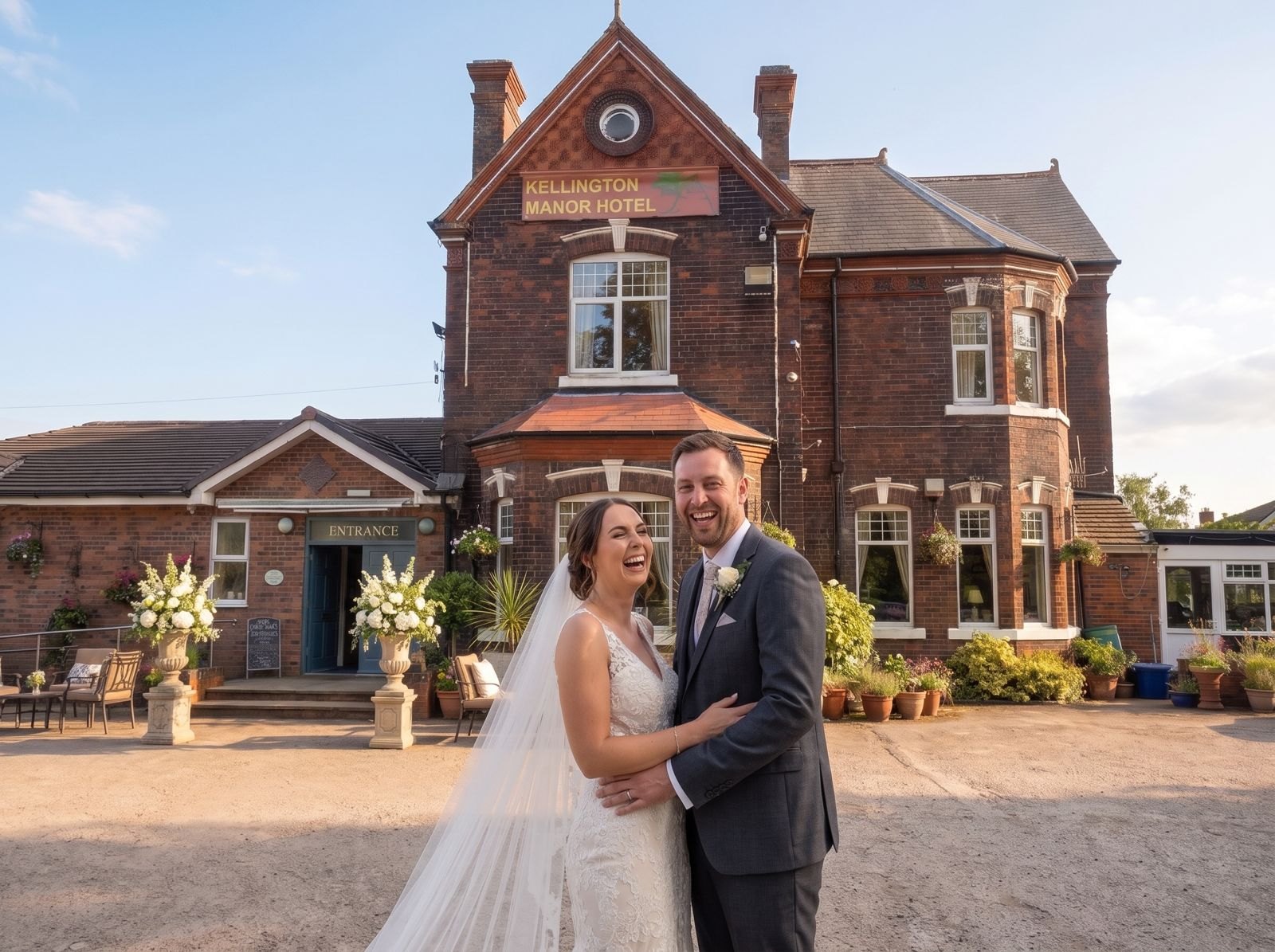 A bride and groom laughing together in front of Kellington Manor in evening light