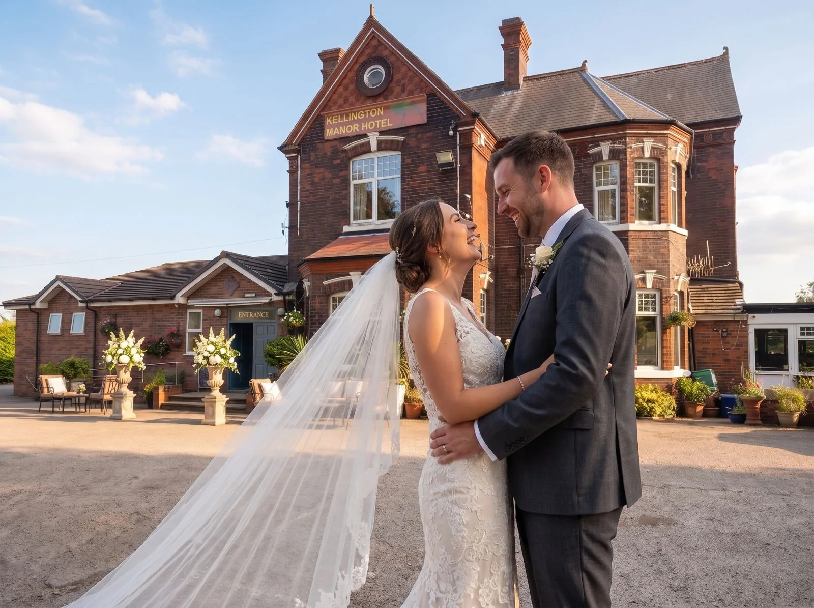 A bride and groom on the drive, her veil carried out behind her